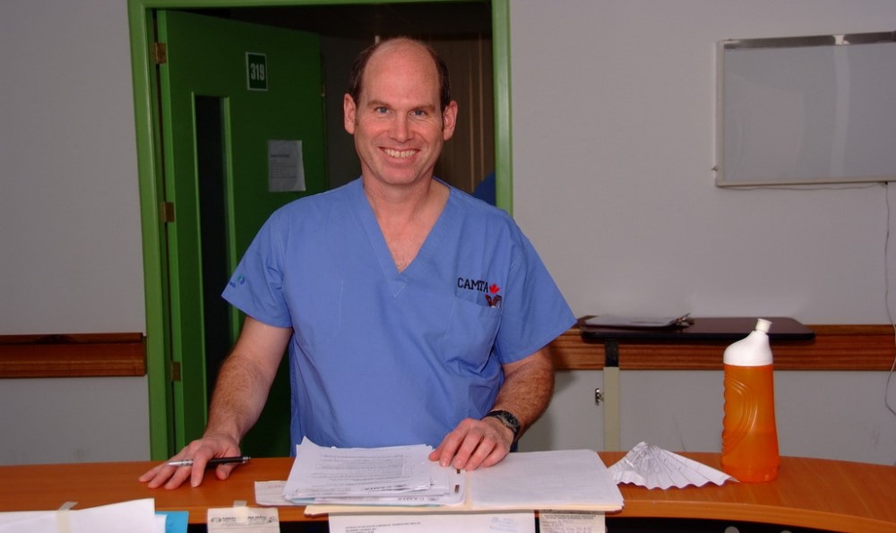 Dr. Vincent in blue lab coat with pen and files